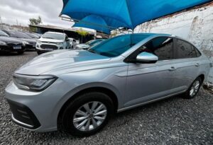 "Volkswagen Virtus prata em excelente estado, vista frontal lateral, estacionado em pátio sob céu azul, destacando o design moderno do sedã."