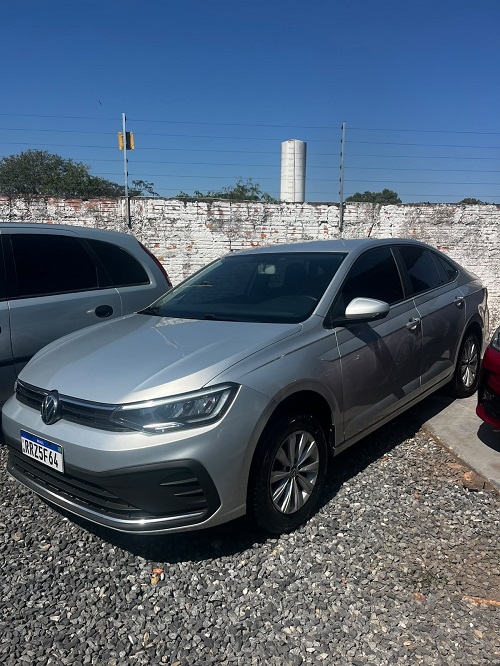 "Volkswagen Virtus prata em excelente estado, vista frontal lateral, estacionado em pátio sob céu azul, destacando o design moderno do sedã."
