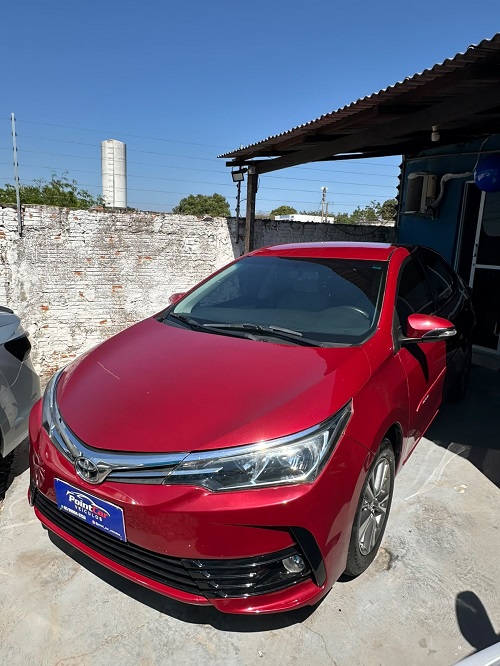 "Toyota Corolla vermelho com design sofisticado, fotografado em ângulo frontal lateral, destacando sua carroceria elegante, faróis modernos e excelente estado de conservação."