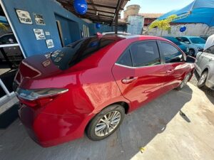 "Toyota Corolla vermelho com design sofisticado, fotografado em ângulo frontal lateral, destacando sua carroceria elegante, faróis modernos e excelente estado de conservação."